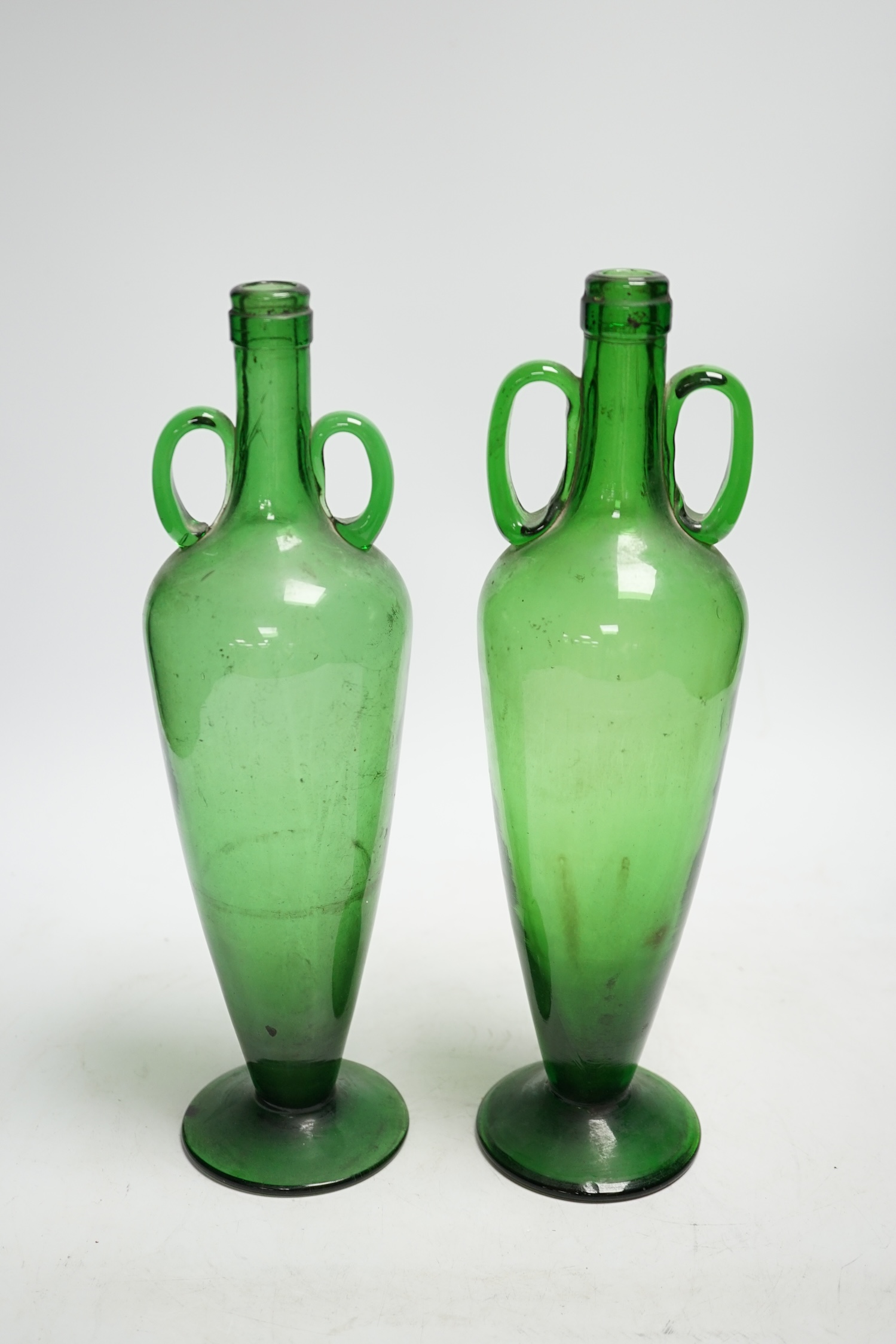 A pair of double handle green glass vases, 33cm